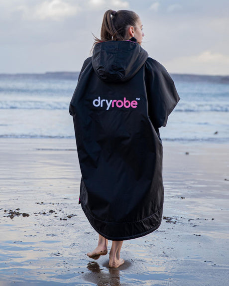 Dryrobe Advance Long Sleeve Kids Kapuzenpullover in Dunkelblau, Rückansicht am Strand getragen