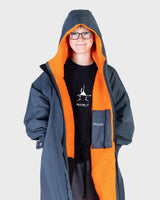 Dryrobe Advance Long Sleeve Kids in Marineblau mit orangefarbener Fleece-Innenseite, Kapuze, Frontansicht auf Kind
