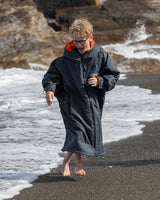 Dryrobe Advance Long Sleeve Kids in Marineblau mit orangefarbenem Kragen, Kind am Strand laufend