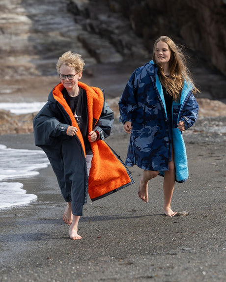 Dryrobe Advance Langarm Kinder in Navy und Blau, zwei Kinder am Strand, Funktionsmaterial mit orange Futter sichtbar