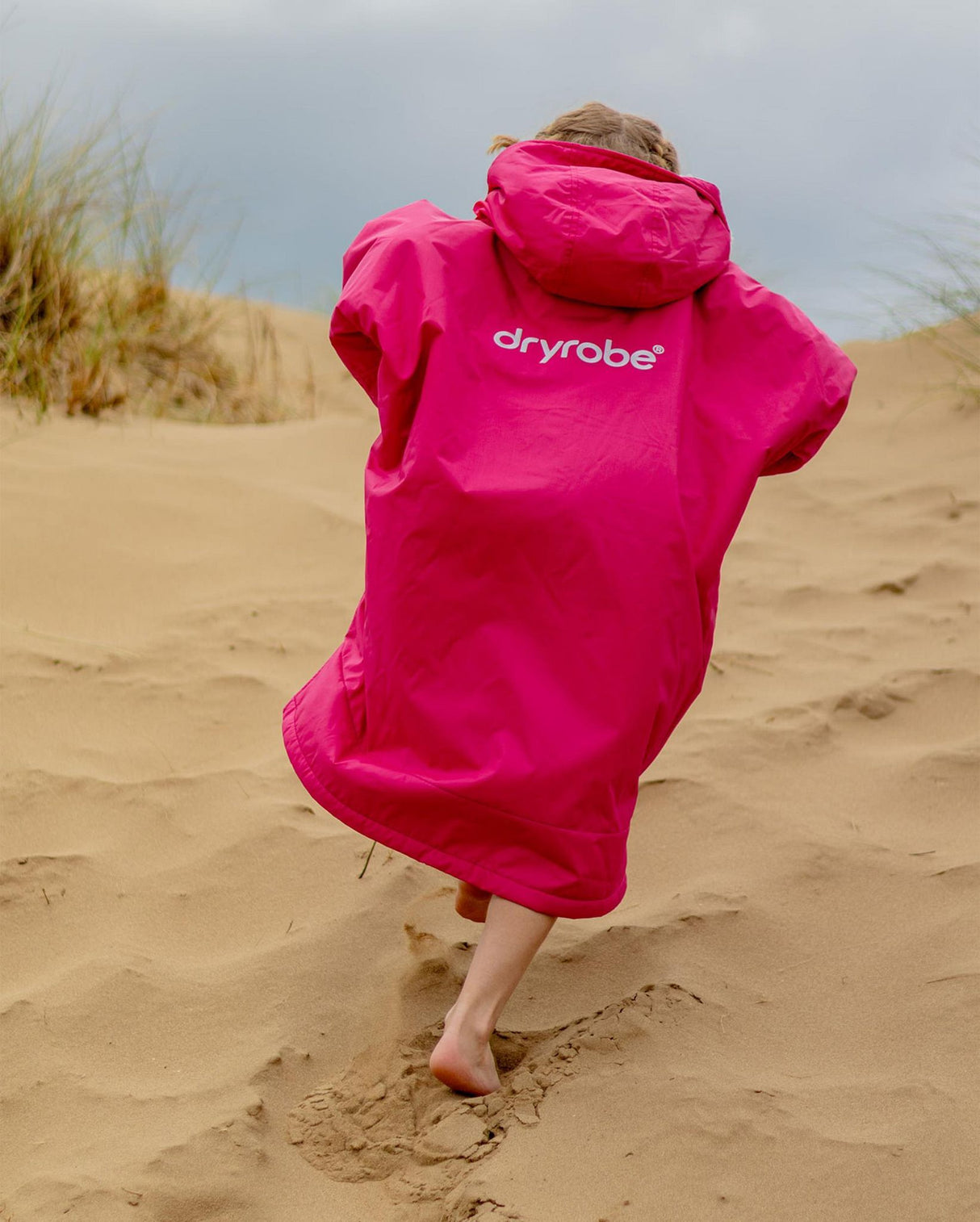 Dryrobe Advance Long Sleeve Kids in Pink, Kapuze und Ärmel, Kind von hinten am Strand, Funktionsmaterial