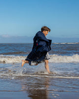 Dryrobe Advance Long Sleeve Kids in Dunkelblau, Kind läuft ins Meer, Funktionsrobe mit langen Ärmeln