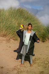 Dryrobe Advance Kurzarm Kids schwarz, Junge trägt Robe am Strand mit Ball