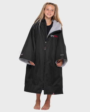 Dryrobe Advance Short Sleeve Kids schwarzer Bademantel mit grauem Fleece-Futter, Frontansicht auf Model