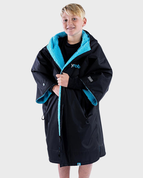 Dryrobe Advance Short Sleeve Kids in Schwarz mit türkisem Fleece-Futter, Frontalansicht eines Kindes in der Robe