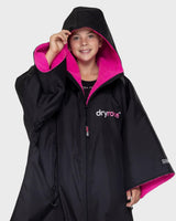 Dryrobe Advance Short Sleeve Kids Umhang in Schwarz mit pinkem Fleece-Futter, Kapuze und Reißverschluss, Frontalansicht
