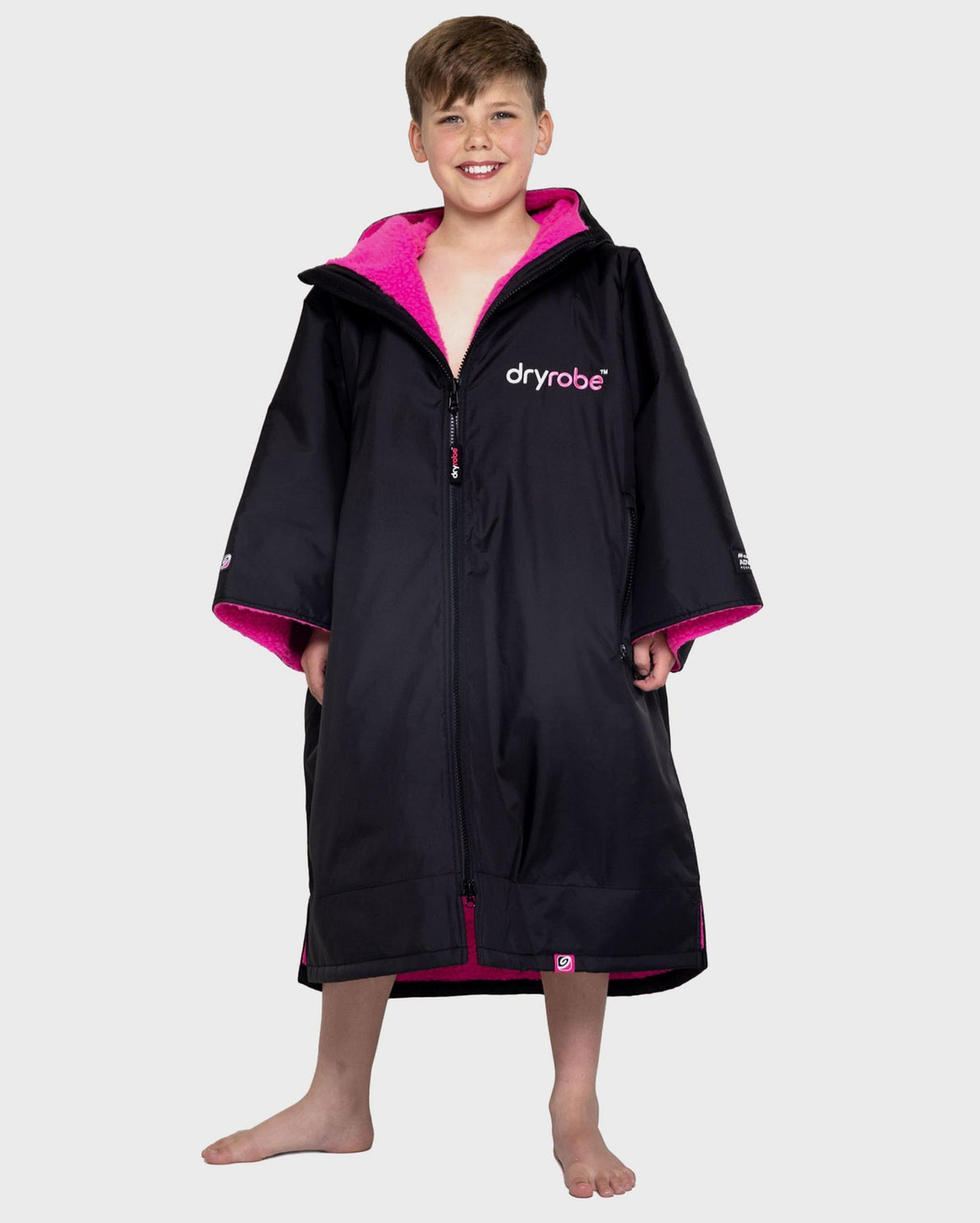 Dryrobe Advance Short Sleeve Kids Umhang in Schwarz mit pinkem Innenfutter, Frontalansicht auf Kind