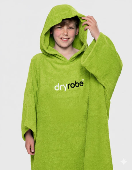 Dryrobe Kids Towel Robe Bio in Limone, Kind trägt grünen Bademantel mit Kapuze und dryrobe-Logo, Frontalansicht