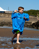 Dryrobe Handtuchmantel Bio Kids in Blau, Kind trägt den Bademantel aus Bio-Baumwolle am Strand