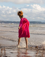 Dryrobe Handtuchmantel Bio Kids in Pink, Kind am Strand mit Bademantel aus Bio-Baumwolle