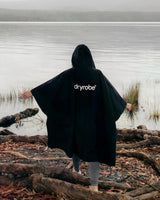 Dryrobe Regen-Poncho schwarz wasserdicht, Person von hinten am See tragend
