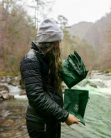 Dryrobe Regen-Poncho in Grün, wasserdicht, getragen von Person am Fluss in Outdoor-Umgebung
