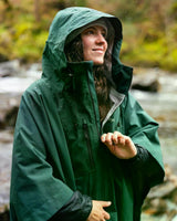 Dryrobe Regen-Poncho in Dunkelgrün, wasserdicht, mit großer Kapuze, getragen von Frau in Außenumgebung
