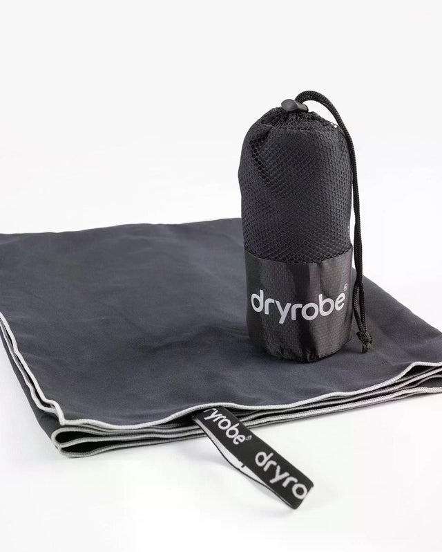Dryrobe Mikrofaserhandtuch in Grau, ausgebreitet mit Tragetasche und Befestigungsband, Produktansicht