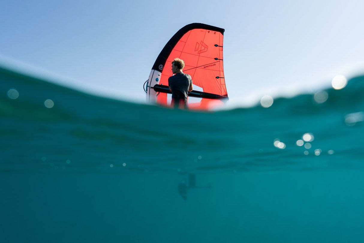 Duotone Unit 2027 Kite in Rot-Schwarz mit Fahrer auf türkisem Wasser, Unterwasserperspektive