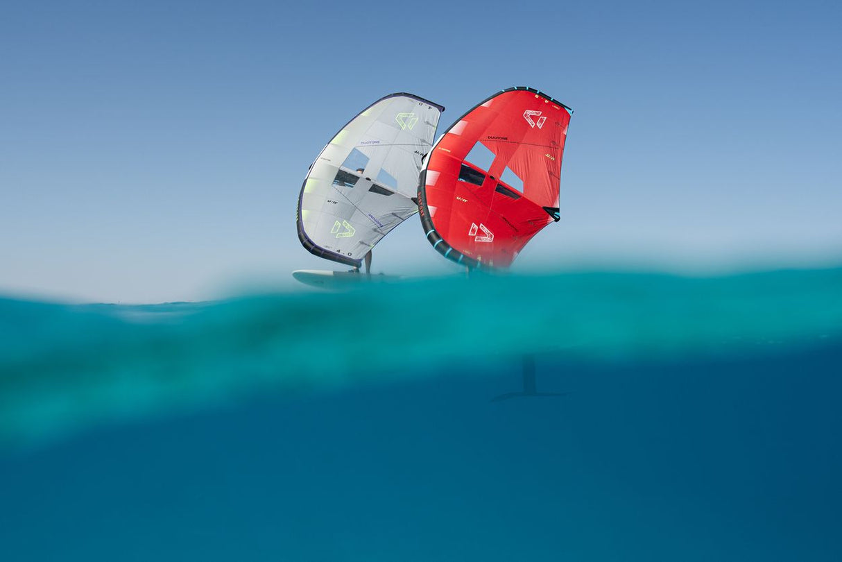 Duotone Unit 2027 Kite in Rot und Weiß über türkisblauem Wasser, Wassersportgerät aus Stoff, Halbansicht auf dem Meer