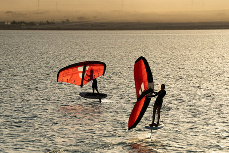 Duotone Unit 2027 Kite in Rot-Schwarz, zwei Kiter mit Boards im Wasser beim Kitesurfen