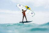 Duotone Unit SLS 2027 Kiteboard mit weißem Segel und gelben Streben, Sportler beim Kitesurfen auf türkisblauem Wasser in Aktion