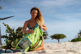 Duotone Unit SLS 2027 Kite in Neon-Gelb und Blau, Frau am Strand präsentiert das Produkt sitzend