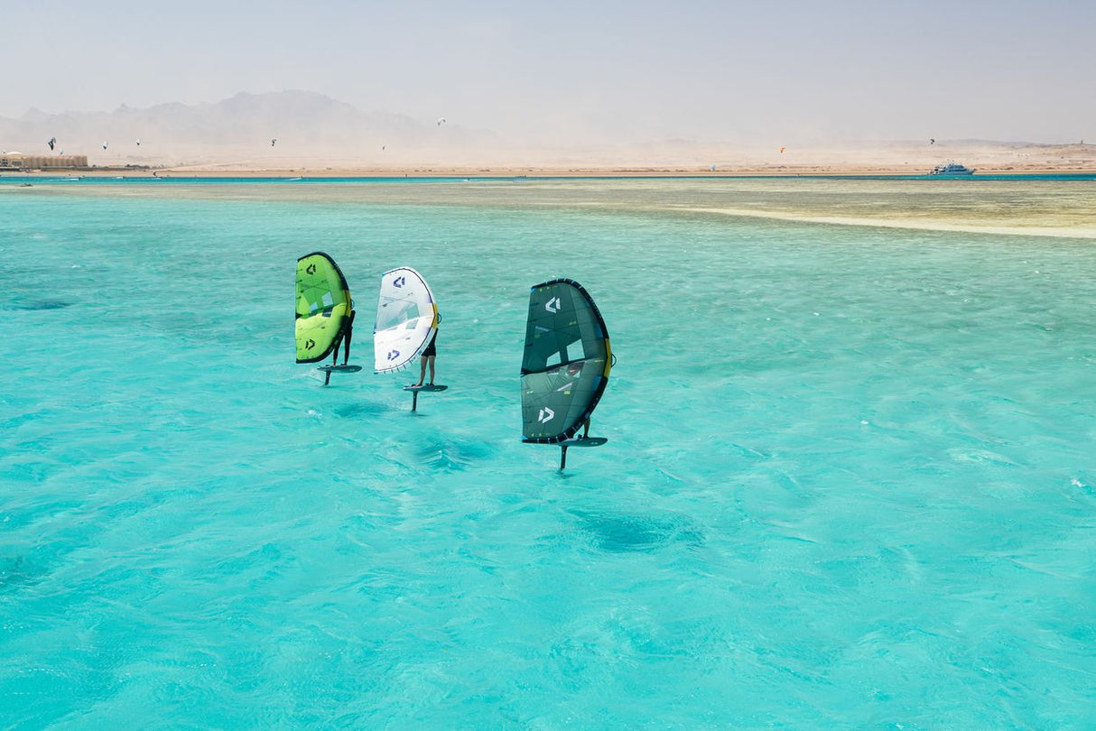 Duotone Unit SLS 2027 Kite in Grün, Weiß und Dunkelgrün, aufgereiht im türkisen Wasser, Frontansicht