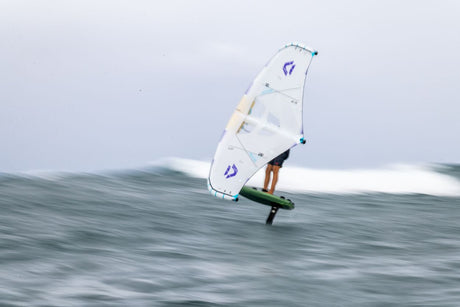 Duotone Unit SLS Concept Blue 2027 Kiteboard mit weißem Segel und blauem Logo auf Welle, Seitenansicht