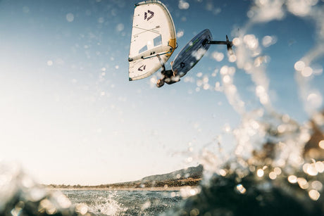 Duotone Unit SLS Concept Blue 2027 Kiteboard in Weiß und Dunkelblau, von unten fotografiert während eines Sprungs über Wasser