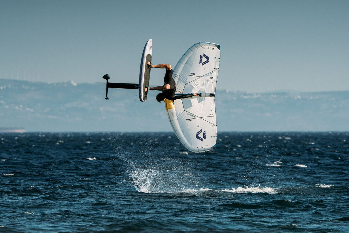 Duotone Unit SLS Concept Blue 2027 Kiteboard in Aktion über dem Wasser, weiß-blaues Design, Seitenansicht