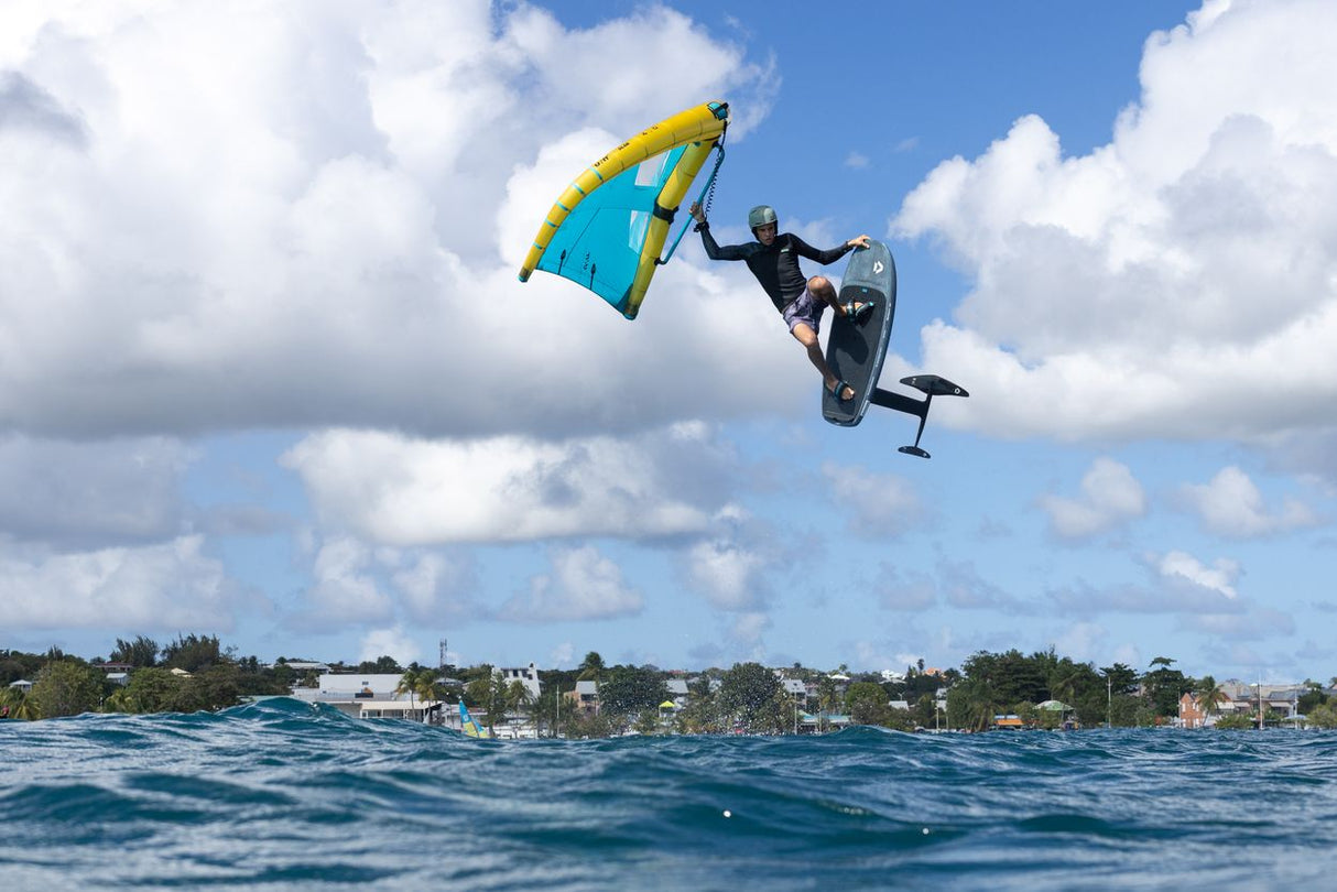 Duotone Sky Style SLS 2027 Kiteboard mit blauem und gelbem Drachen, Fahrer in Aktion über Wasser springend