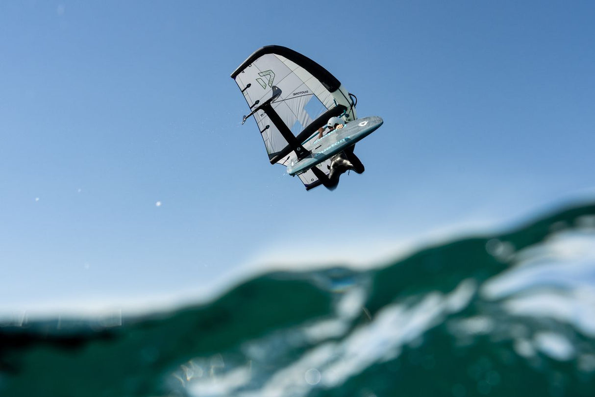 Duotone Sky Style SLS 2027 Kiteboard mit weiß-blauem Drachensegel in der Luft über dem Wasser, Frontalansicht