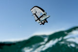 Duotone Sky Style SLS 2027 Kiteboard mit weiß-blauem Drachensegel in der Luft über dem Wasser, Frontalansicht