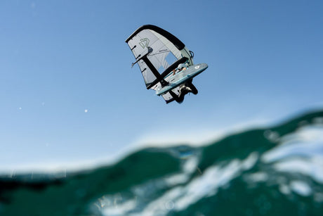 Duotone Sky Style SLS 2027 Kiteboard mit weiß-blauem Drachensegel in der Luft über dem Wasser, Frontalansicht