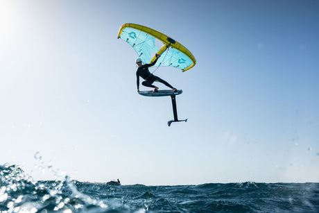 Duotone Sky Style SLS 2027 Kiteboard mit gelbgrünem und blauem Doppelton-Design, Athlet in Aktion über Wasser springend