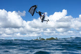 Duotone Sky Style 2027 Kiteboard in Blau-Schwarz, Athlet in Sprung über Meer mit Insel im Hintergrund