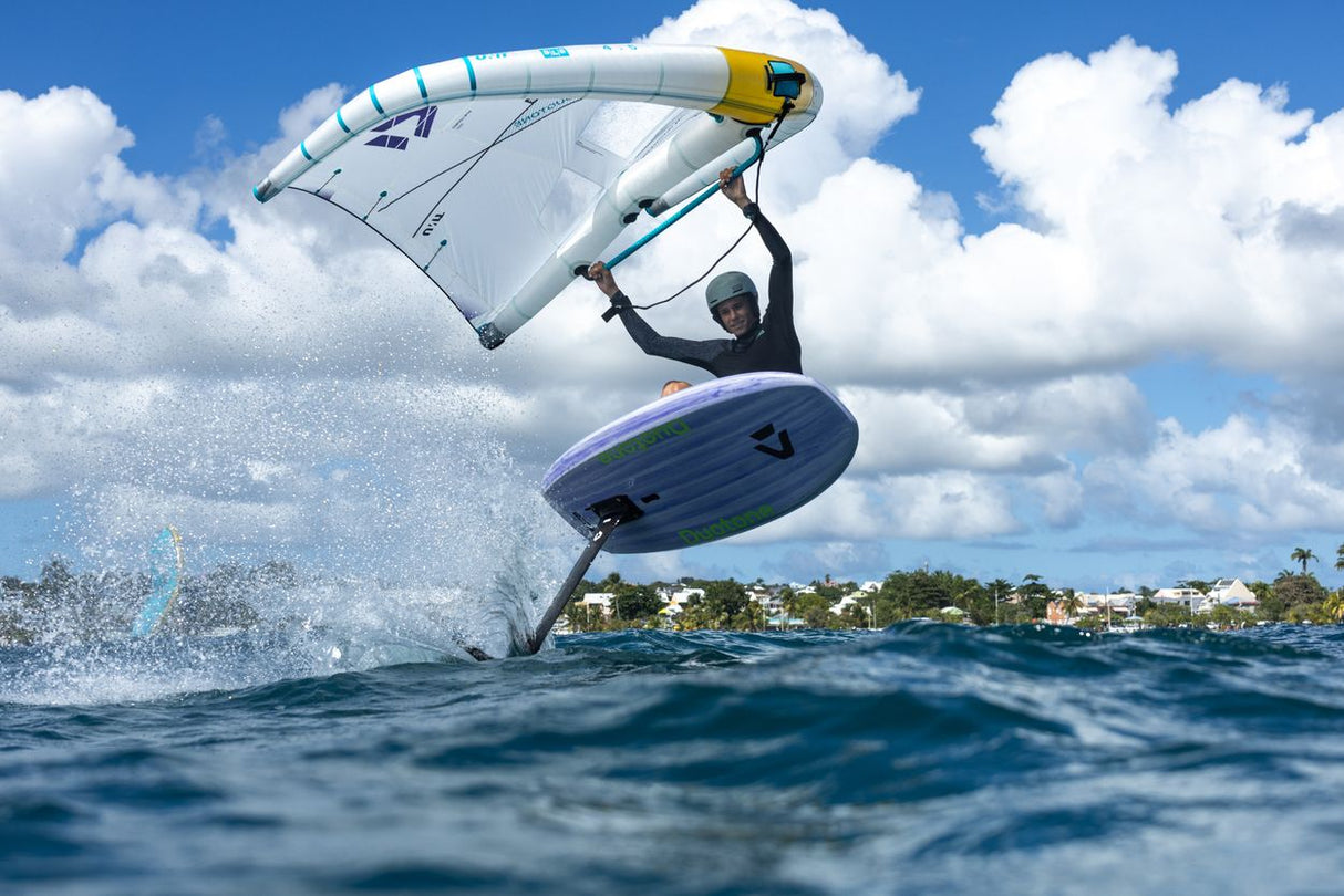 Duotone Sky Style 2027 Kiteboard weiß-blau mit gelbem Griff in Aktion über Wasser, Sprungperspektive