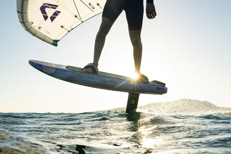 Kitesurfer mit Duotone Sky Style 2027 Kite und blauem Board im Wasser, Frontalansicht bei Sonnenuntergang