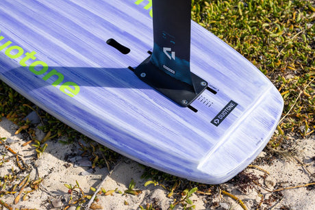 Duotone Sky Style 2027 Kiteboard mit lila-weißem Duotone Design und schwarzer Finne, Draufsicht auf Sand