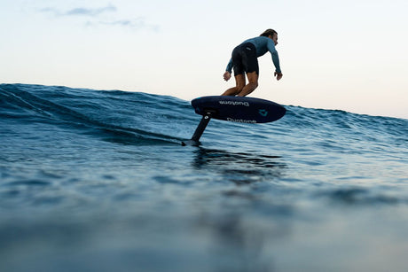 Duotone Crush SLS 2027 Foil-Board in Schwarz, Fahrer auf Welle im Meer, Seitenansicht
