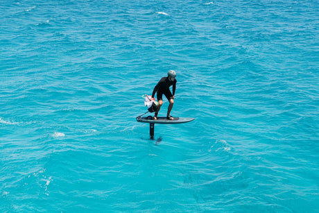 Duotone Skybrid SLS 2027 Kiteboard in Aktion auf türkisblauem Wasser, Fahrer in Seitenansicht, schwarzes Outfit