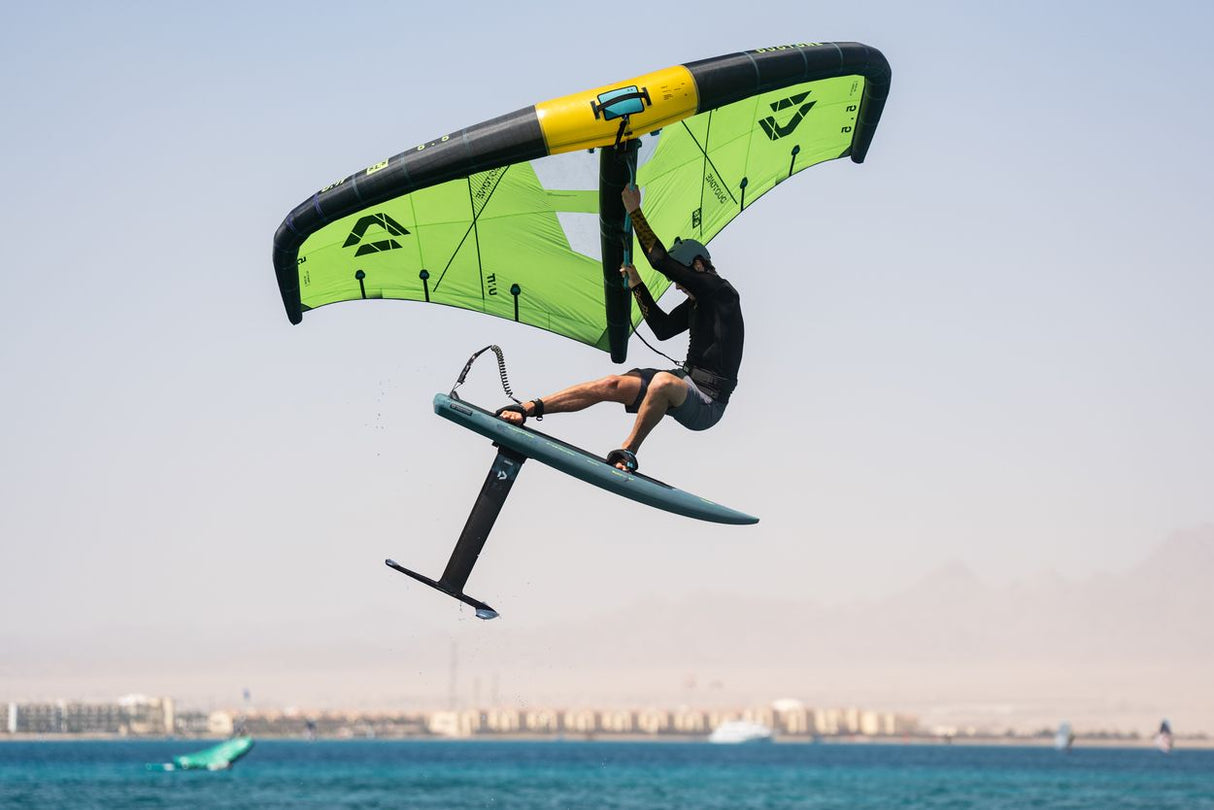Duotone Skybrid SLS 2027 Kiteboard neongelb-schwarz mit Sportler in Aktion über dem Meer