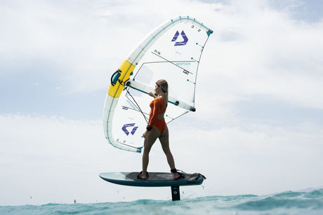 Duotone Skybrid SLS 2027 Kite mit weißem Segel, gelben und blauen Details, Kitesurfer auf Board im Wasser