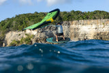 Duotone Skybrid SLS 2027 Kite in Grün-Gelb, Wassersportler beim Kiteboarden mit Klippe im Hintergrund