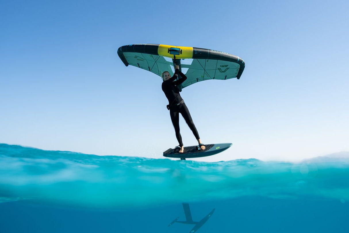 Duotone Skybrid SLS 2027 Kiteboard mit grünem Segel und gelbem Trapez, Fahrer auf türkisblauem Wasser in Aktion