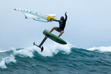 Duotone Trace SLS 2027 Kiteboard weiß-blau mit gelbem Auftrieb, Kiter in Aktion über Meereswellen