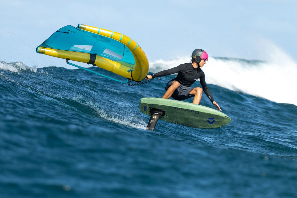 Duotone Trace SLS 2027 Kiteboard in Blau-Gelb, Rider in Aktion auf dem Wasser mit Kite, Seitenansicht