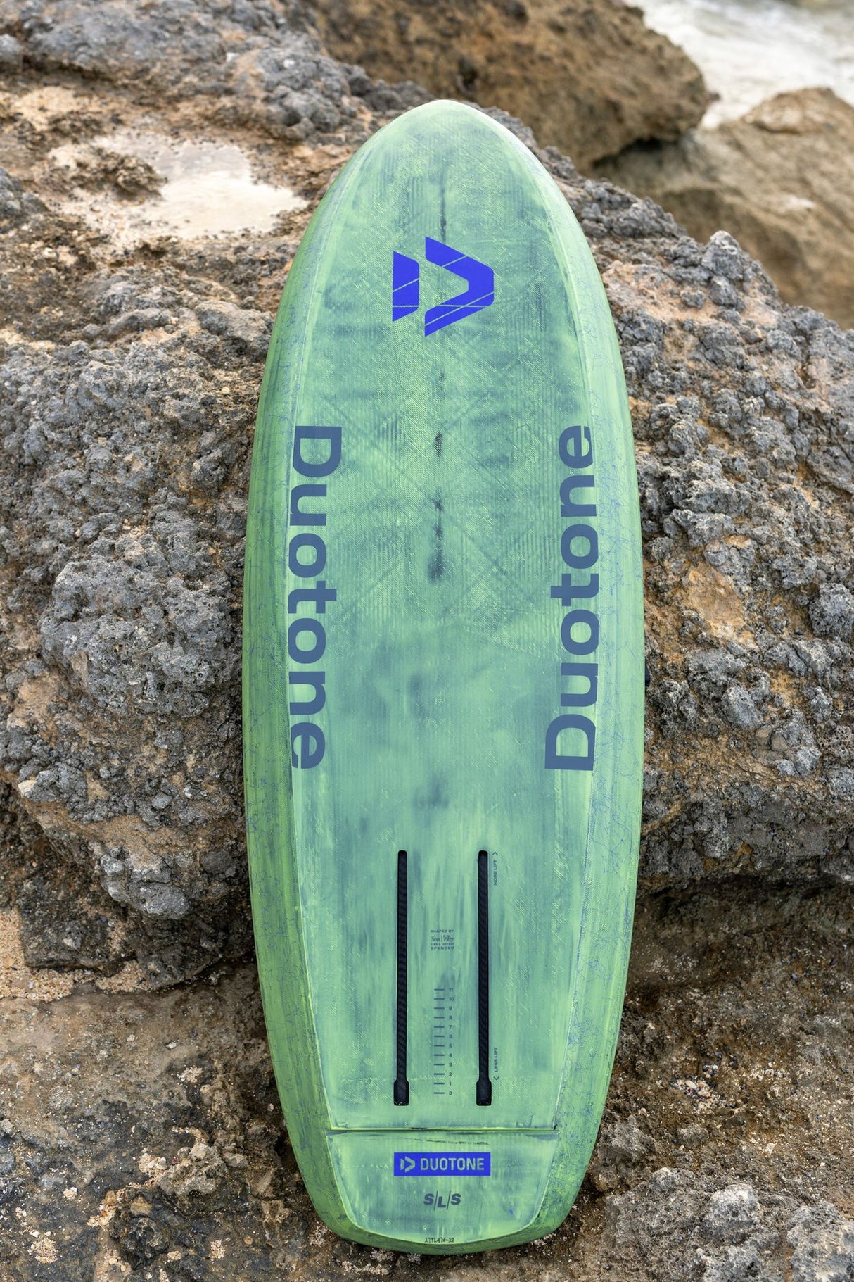 Duotone Trace SLS 2027 Wakeboard in Grün mit blauem Logo, Draufsicht auf Stein