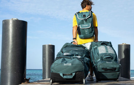 Duotone Combibag 2027 Reisetasche in Dunkelgrün, getragen und präsentiert von einer Person am Steg mit Meerblick