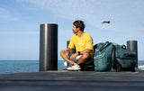 Duotone Combibag 2027 in Grün-Blau neben einer Person am Meer, Seitenansicht der Reisetasche