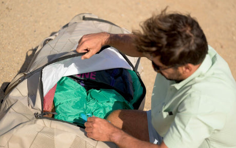 Duotone Combibag 2027 Reisetasche offen mit Kleidung, Draufsicht am Strand, grau und grün