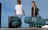 Duotone Boardbag Single Twintip 2027 in Dunkelgrün, Transporttasche mit Tragegriffen, zwei Personen am Strand