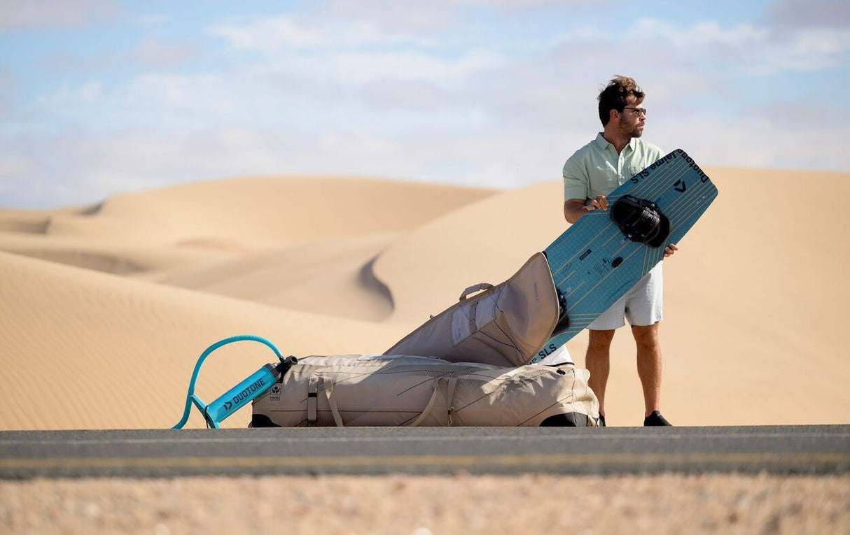 Duotone Boardbag Single Twintip 2027 in Blau, Transporttasche für Twintip-Board, Mann trägt Board in Wüstenlandschaft